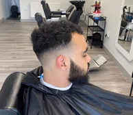 A curly top with a mid skin fade and full beard