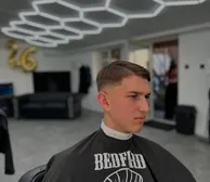 A side part with a low fade, under the hexagon ceiling lights